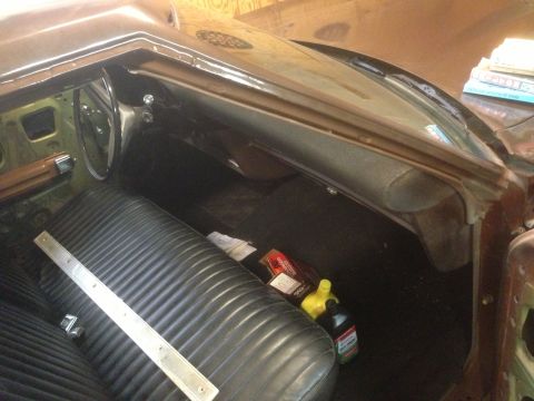 1972 Ford Ranchero - The interior of a 1972 Ford Ranchero shows a black bench seat and dashboard, with bottles of fluid on the floor.