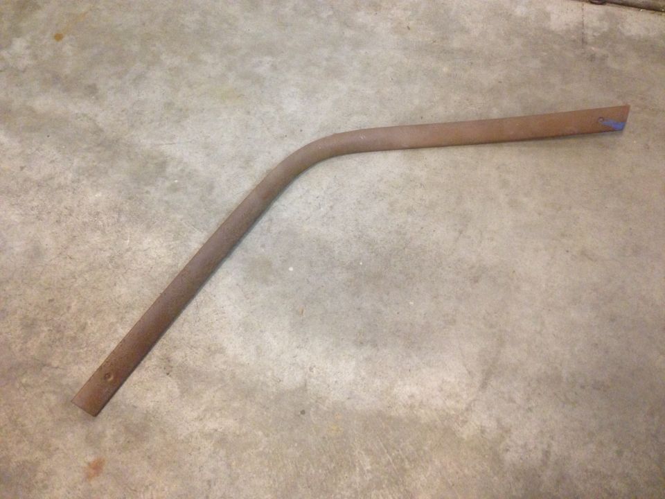 Rusted metal rod with a bend, lying on concrete floor