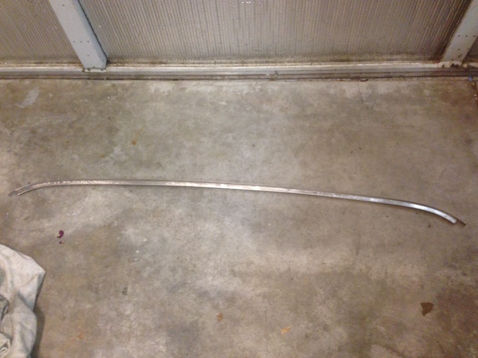 long, curved chrome trim piece on concrete floor
