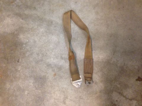 1972 Ford Ranchero - A tan seatbelt with metal hardware is shown lying on a concrete surface.