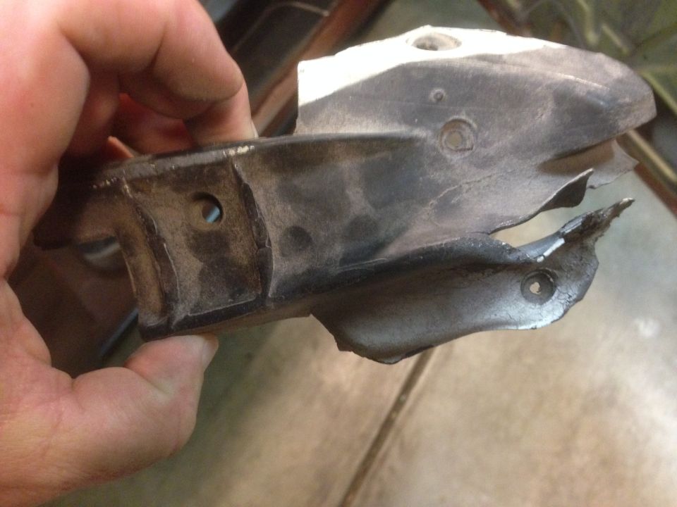 Hand holding a damaged metal bracket with mounting holes