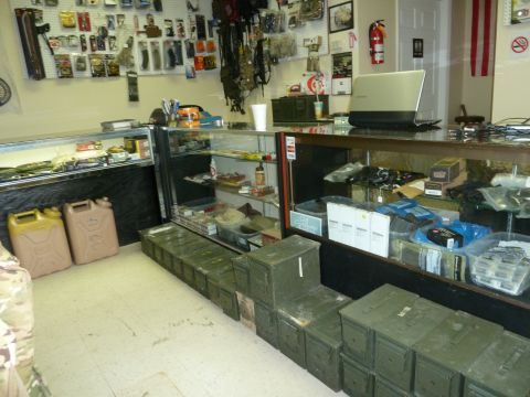 1992 Ford Mustang - A store interior displays various goods on shelves and in cases, with stacked ammo cans on the floor.