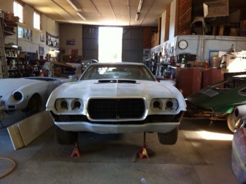 1972 Ford Ranchero - A 1972 Ford Ranchero is seen on jack stands in a garage, with other vehicles in the background.