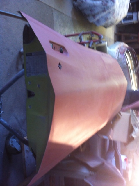 1972 Ford Ranchero - A car door, prepped with primer, sits on a stand in a workshop.