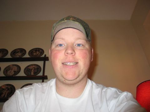 1995 Ford Bronco - Man in a baseball cap and t-shirt smiles for the camera, with decorative plates on a shelf behind him.
