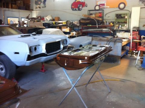 1972 Ford Ranchero - A car is being worked on in a garage, with parts laid out and other vehicles in the background.