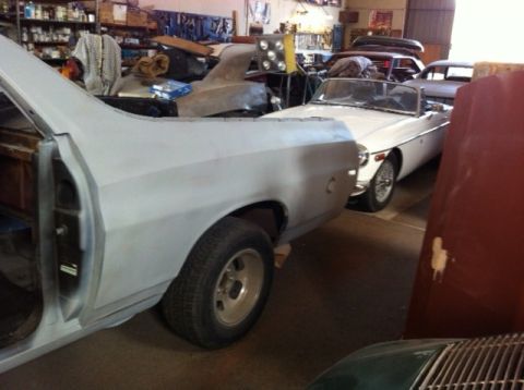 1972 Ford Ranchero - A white convertible sports car is parked in a garage next to a vehicle undergoing repairs.