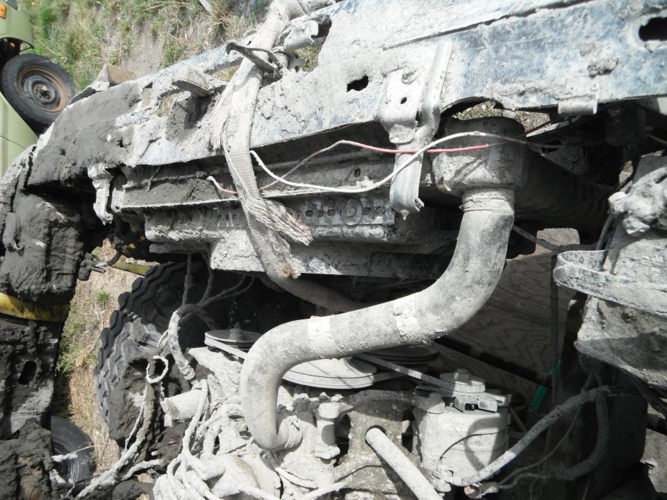 Mud-covered engine and radiator hoses of a vehicle, with a tire visible on the left