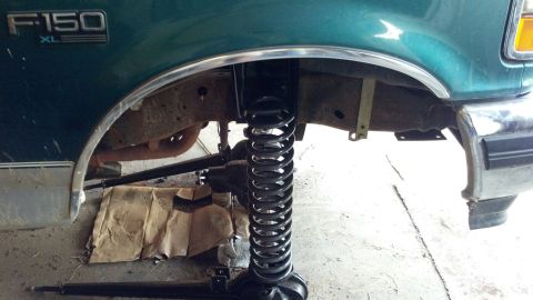 1996 Ford F-150 - Close-up of the front suspension of a green 1996 Ford F-150 XL, with the coil spring visible.