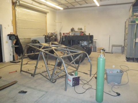 1961 International Scout 800 - A custom roll cage is being constructed for a vehicle chassis in a garage setting.