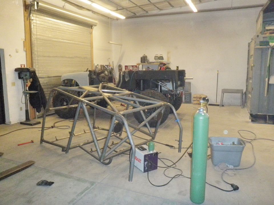 Metal roll cage and vehicle chassis in a workshop with welding equipment