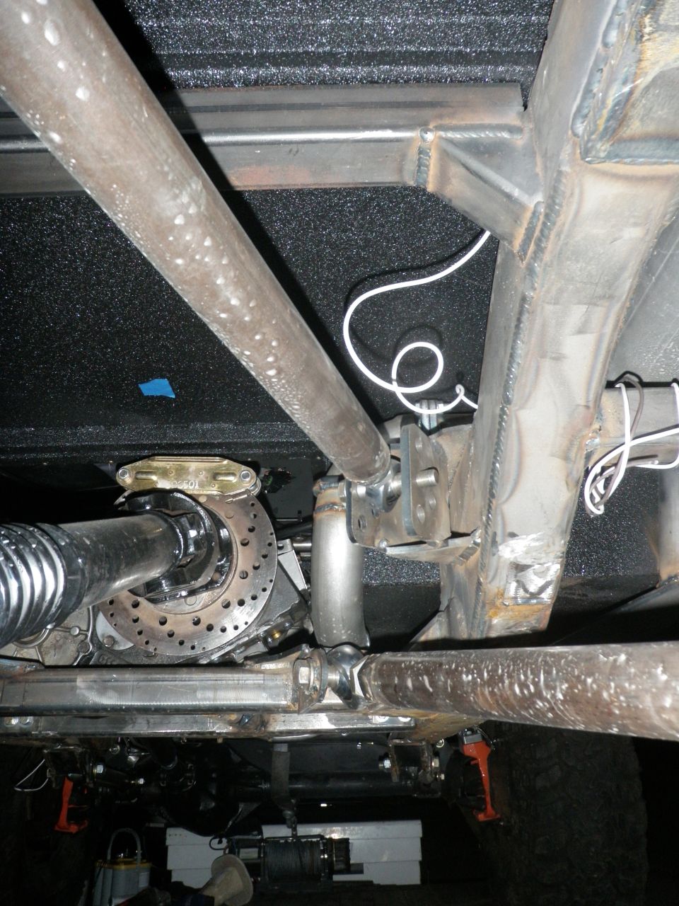 Underbody view of exhaust pipe, driveshaft, and suspension parts