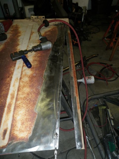 1961 International Scout 800 - A car hood is undergoing repair with various tools and equipment in a workshop setting.