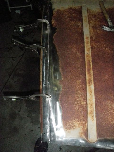 1961 International Scout 800 - Metal panel undergoing repair with clamps and evidence of rust.