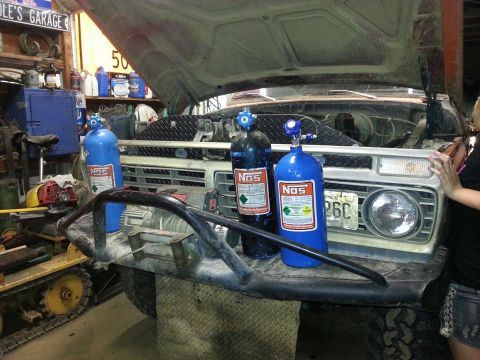 1978 Ford Bronco - Three NOS bottles are mounted on the front bumper of a vintage truck with the hood open.