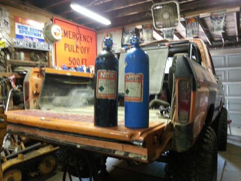 1978 Ford Bronco - Two nitrous oxide tanks are placed in the bed of an orange Ford Bronco, possibly for modification.
