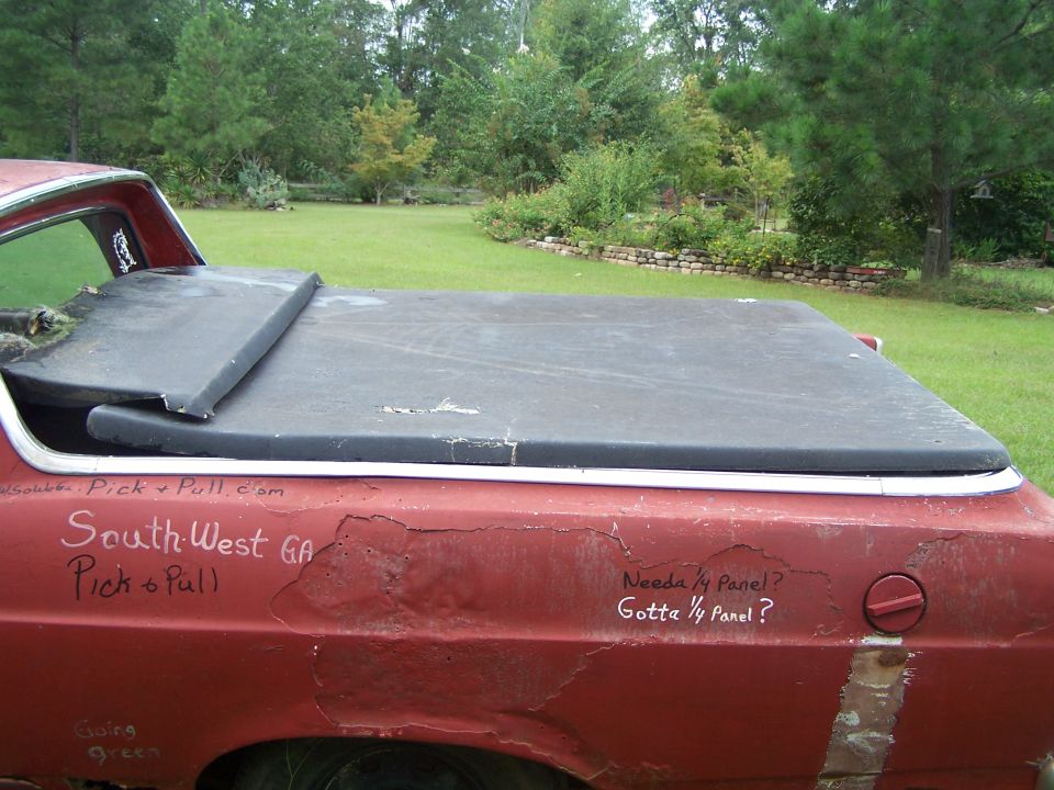 Red pickup truck bed with a black tonneau cover, showing rust and handwritten text. Needs 1/4 panel?
