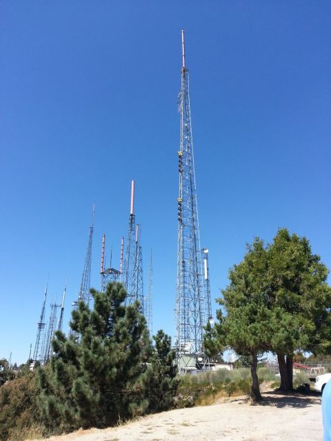 1995 Ford Taurus - A collection of tall radio towers stands against a bright blue sky, surrounded by green trees and foliage.