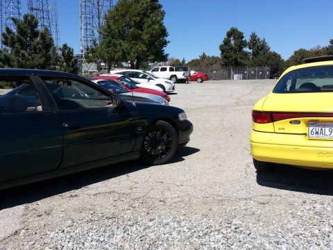 1995 Ford Taurus - A yellow sedan is parked in a lot with other vehicles visible in the background.