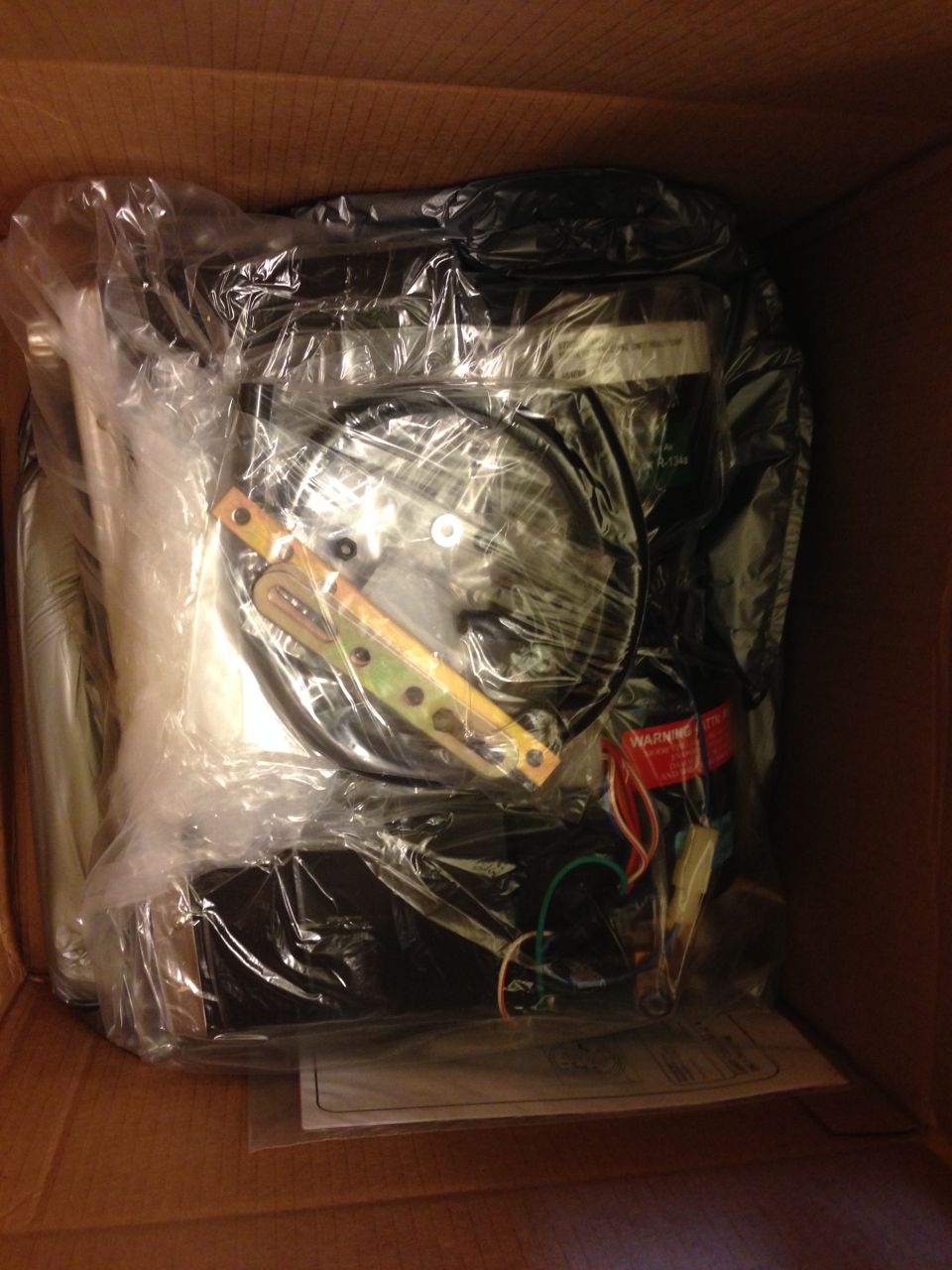 Unidentified part wrapped in plastic inside a cardboard box