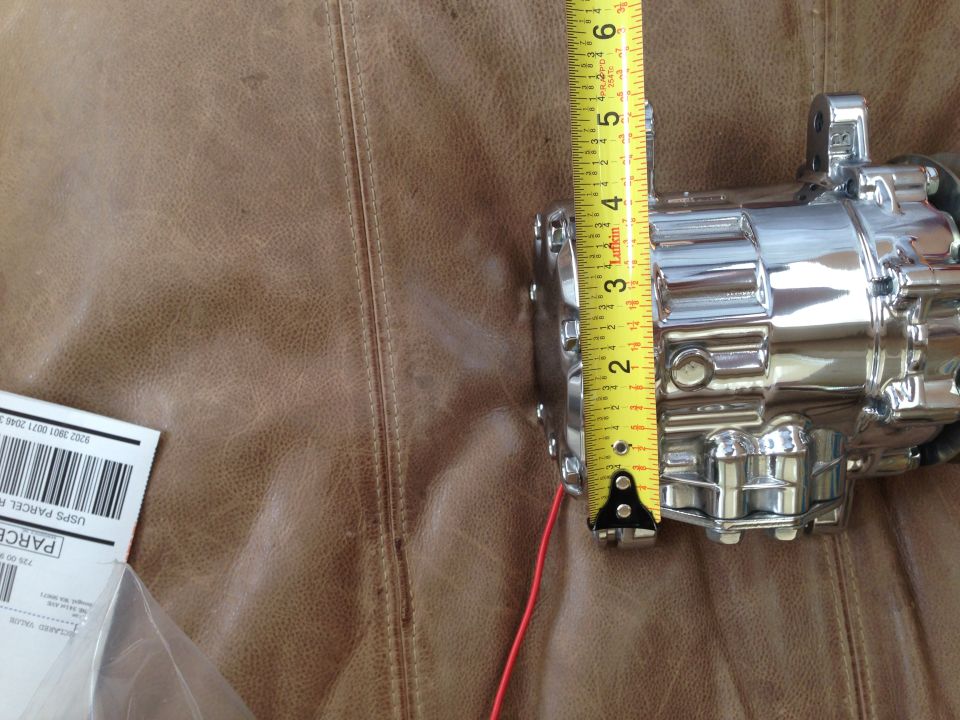 Chrome-plated automotive part being measured with a yellow tape measure. A USPS shipping label is visible on the left