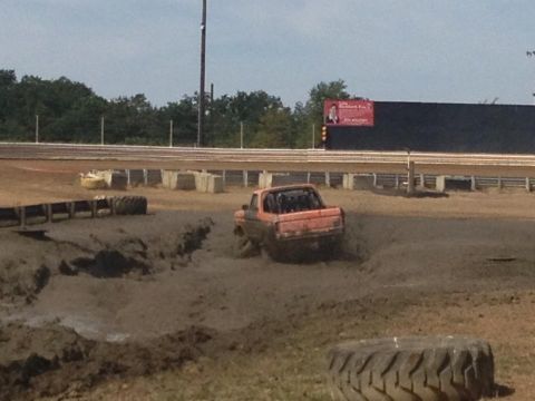 1978 Ford Bronco - Pickup truck navigates a muddy track during an event.