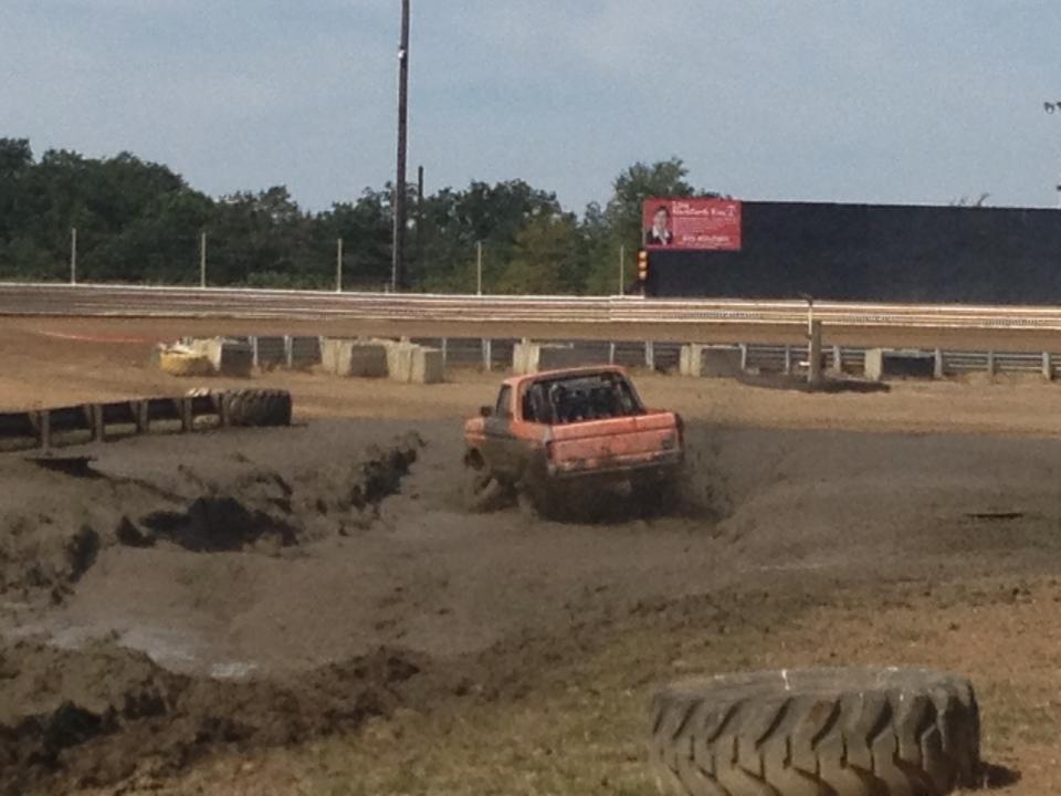 Orange pickup truck driving through mud
