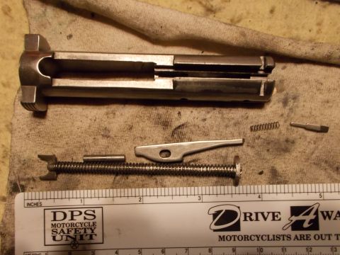 2012 Ford Mustang - A disassembled firearm slide and spring are laid out next to a ruler for scale.