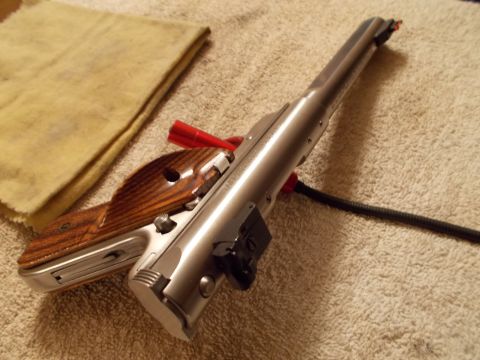 2012 Ford Mustang - A close-up view of a firearm part, a silver metallic finish and a wooden grip, resting on a textured surface.