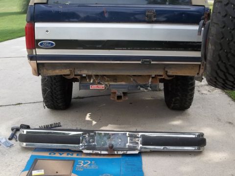 1995 Ford Bronco - The rear of a 1995 Ford Bronco is shown with its bumper removed, revealing the hitch and wiring. A spare tire is mounted to the right side.