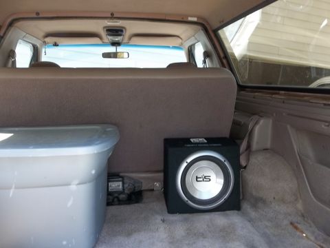 1995 Ford Bronco - Vehicle interior cargo area with a storage bin and a subwoofer. Year unknown.