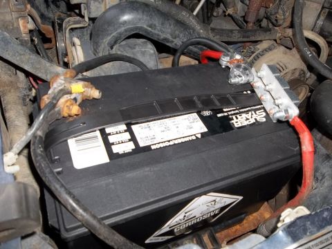 1995 Ford Bronco - Close-up of a vehicle's battery and surrounding engine components, showing wiring and hoses.