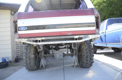 1979 Ford Bronco - Maroon Ford Bronco rear end on jack stands, with a blue pickup truck in the background.