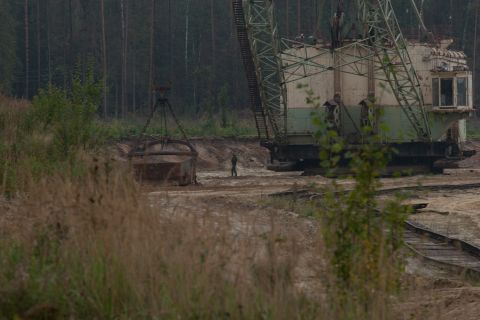 1987 Ford Bronco - A massive excavator and its dragline bucket are seen in a quarry, with a lone figure standing in the distance.