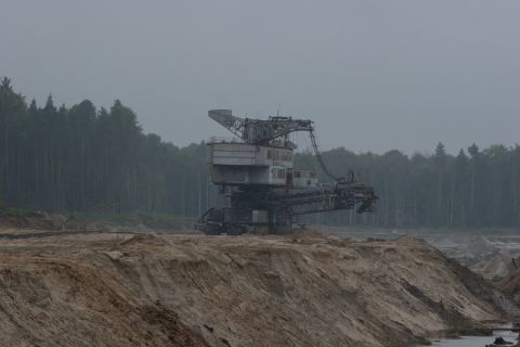 1987 Ford Bronco - A large bucket-wheel excavator operates in a quarry, with a dense forest visible behind it.