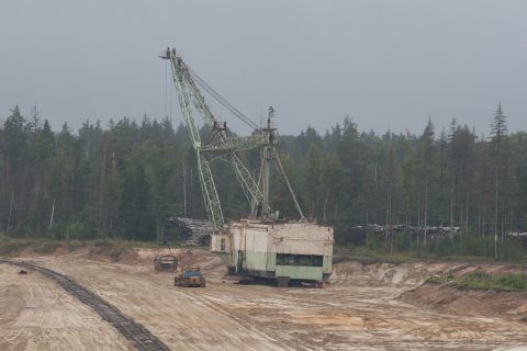 1987 Ford Bronco - A large dragline excavator and a smaller bulldozer operate in a quarry, with a dense forest visible in the background.