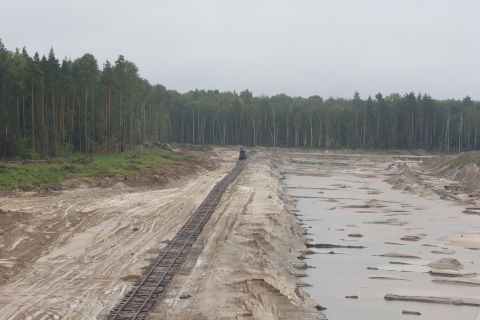 1987 Ford Bronco - A construction site features train tracks and a distant vehicle amidst a wooded landscape.