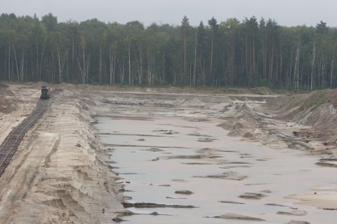1987 Ford Bronco - A train travels on tracks through a sand quarry, with a dense forest bordering the landscape.