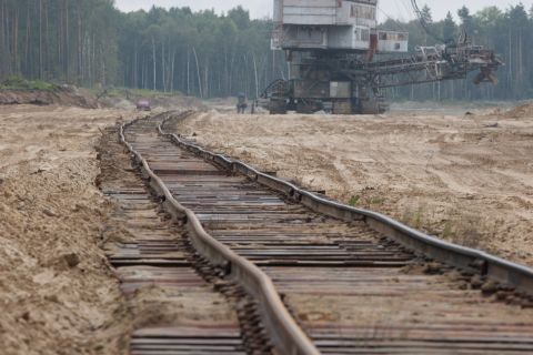 1987 Ford Bronco - Industrial excavator and railroad tracks in a barren landscape with a distant red vehicle.