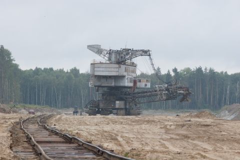 1987 Ford Bronco - A massive bucket-wheel excavator stands idle in a quarry, with railway tracks leading towards it.