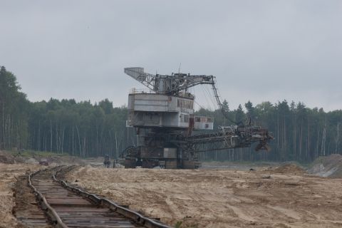 1987 Ford Bronco - A massive bucket-wheel excavator dominates the landscape of a sand quarry, with train tracks leading towards it.