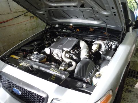 2001 Ford Crown Victoria - The engine bay of a 2001 Ford Crown Victoria, with the hood open, revealing the V8 engine and surrounding components.