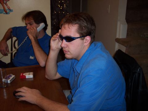 1990 Ford Bronco - Two men are seated at a table, one on the phone and the other wearing sunglasses.