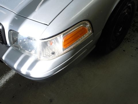 2001 Ford Crown Victoria - Close-up of the front passenger side of a silver 2001 Ford Crown Victoria, highlighting the headlight assembly.