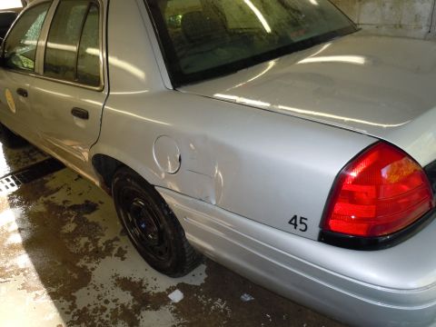 2001 Ford Crown Victoria - Rear view of a silver 2001 Ford Crown Victoria showing a dent on the quarter panel and a '45' decal.