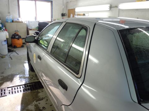 2001 Ford Crown Victoria - A silver sedan is parked in a garage, with a wet floor and a shop vac visible.
