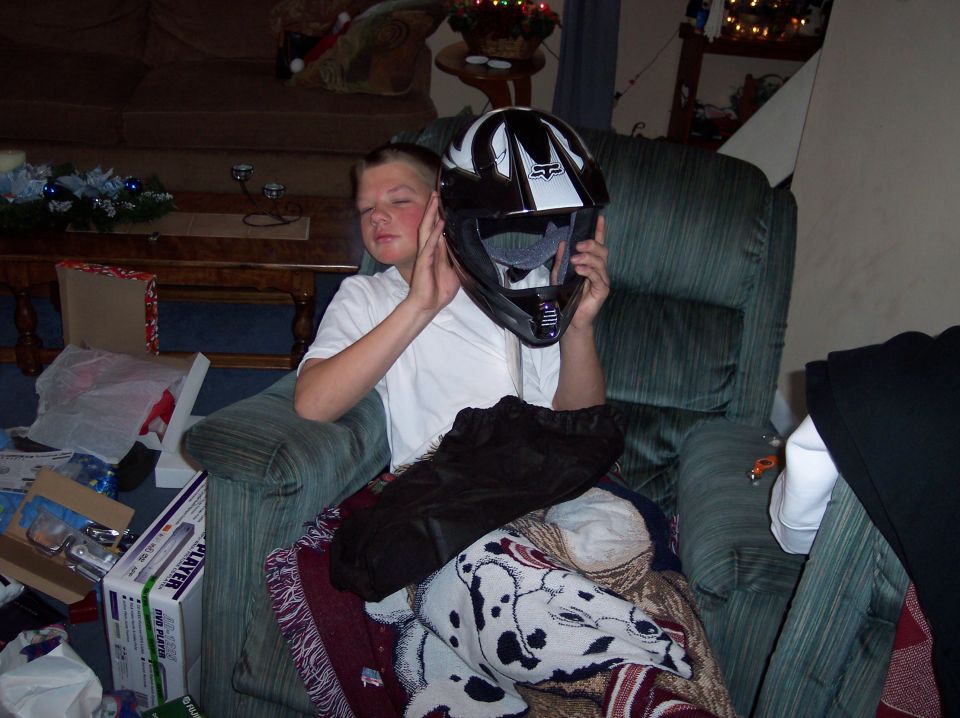 Boy holding a black and white motocross helmet in a living room