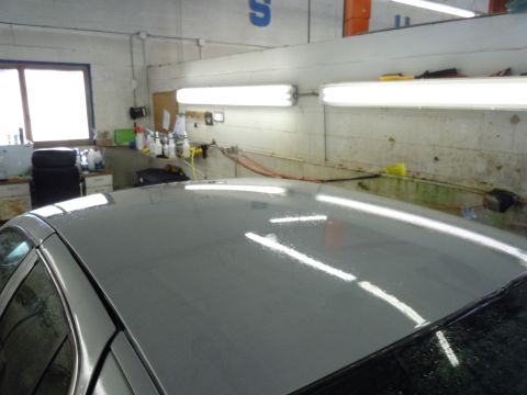 2001 Ford Crown Victoria - The top of a gray car is visible in a workshop setting, with water droplets on its surface.