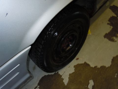 2001 Ford Crown Victoria - A close-up view of a vehicle's wheel well and tire, with liquid spilled on the concrete floor.