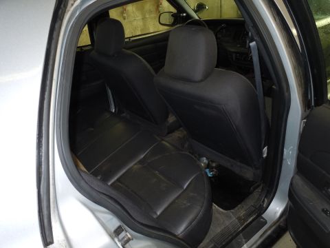 2001 Ford Crown Victoria - Interior view of a silver car's rear passenger area, showing black leather seats and door panel.